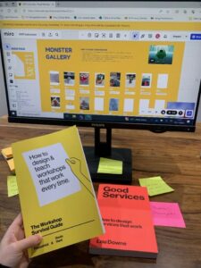 Image of a desktop screen with post-it notes and the book 'The Workshop Survival Guide' on the desk